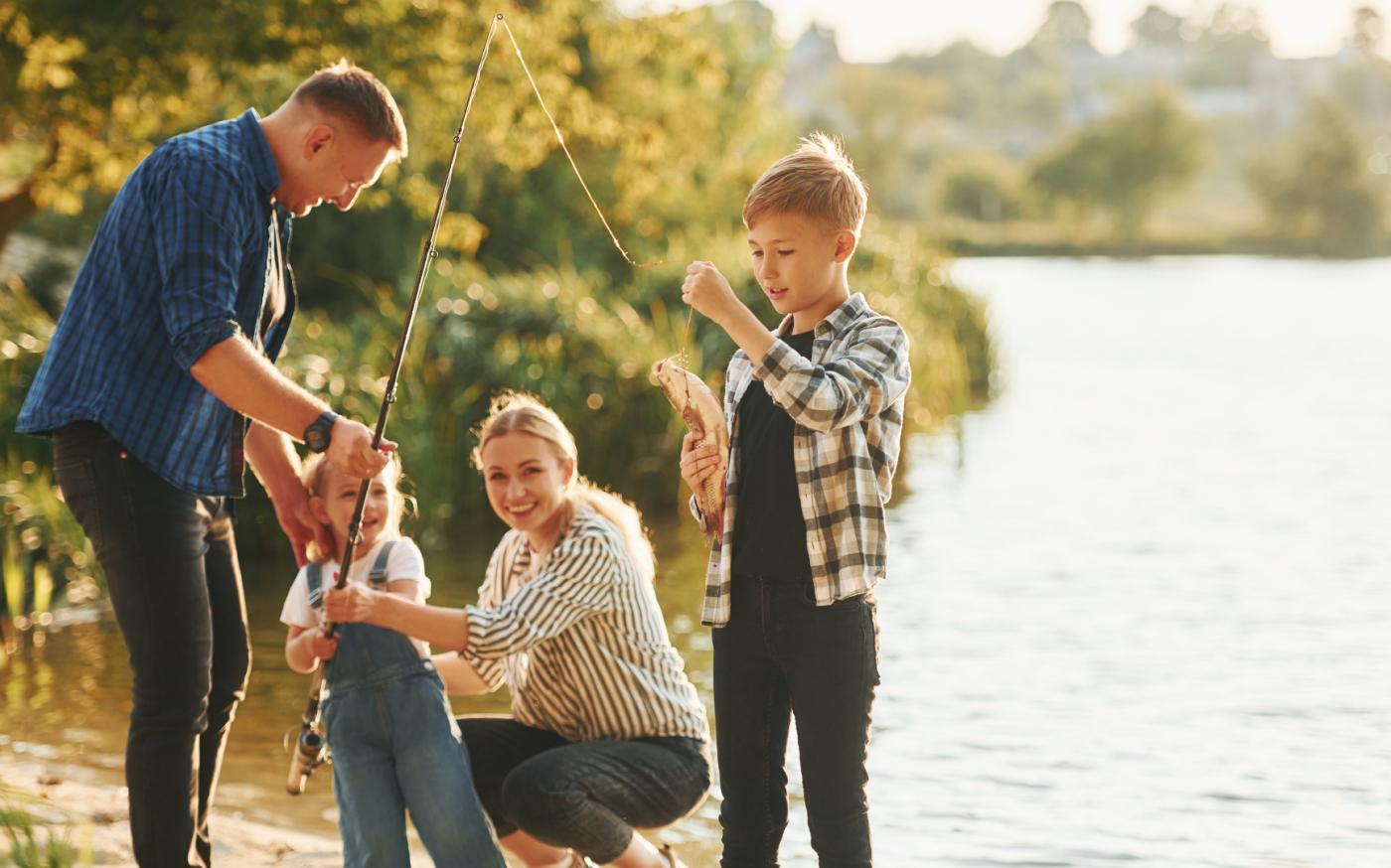 Family of four fishing on the edge of a lake